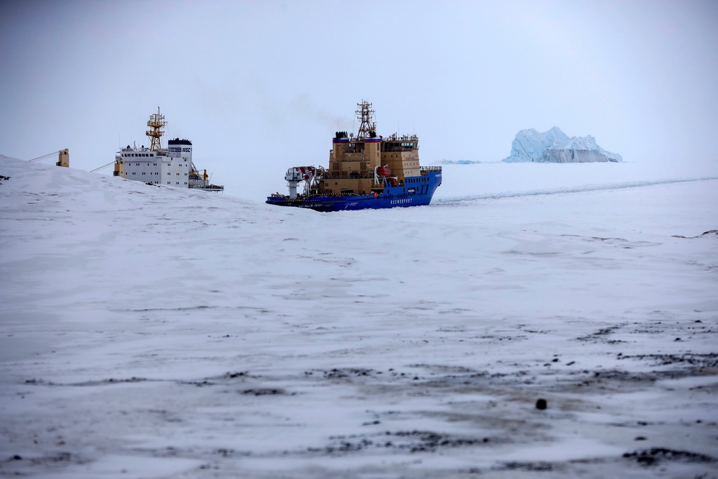 FILE - An Icebreaker makes the path for a cargo ship with an iceberg in the background near a port on the Alexandra Land island near Nagurskoye, Russia, May 17, 2021. (AP Photo/Alexander Zemlianichenko, File)