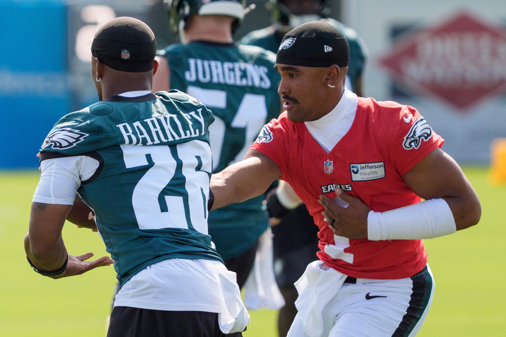 Philadelphia Eagles quarterback Jalen Hurts (1) hands the ball off to running back Saquon Barkley (26) during practice at the team's NFL football training camp in Philadelphia, Wednesday, July 29, 2026. (AP Photo/Chris Szagola)