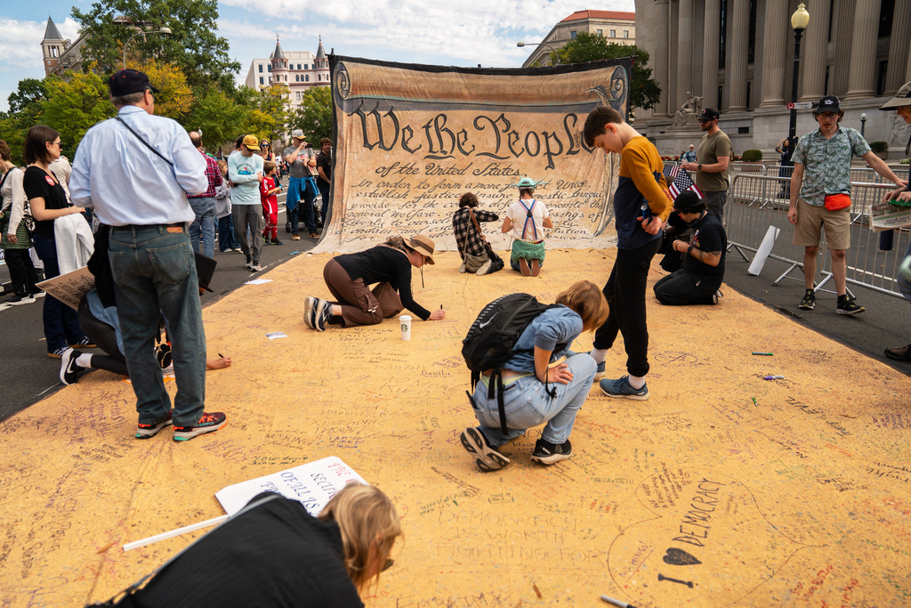 Attendees sign a banner representing the U.S. Constitution during a No Kings protest, Saturday, Oct. 18, 2025, in Washington. (AP Photo/Allison Robbert)