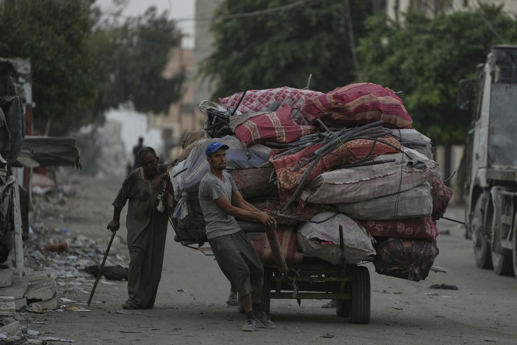 Displaced Palestinians fleeing Jabaliya move with their belongings on a street in Gaza City, Tuesday, Aug. 26, 2025. (AP Photo/Jehad Alshrafi)