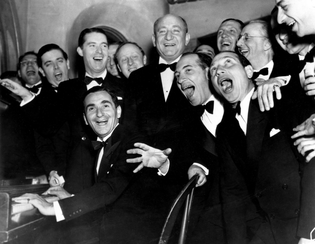 FILE - Irving Berlin, at the piano, and friends celebrate his 25th year since he wrote "Alexander's Rag Time Band" at a banquet in his honor in Hollywood, Ca., Jan. 20, 1936. Standing behind Berlin, at right, is Joseph Schenck, film producer. In front row singing together are two of the Marx Brothers, Chico and Harpo. (AP Photo, File)