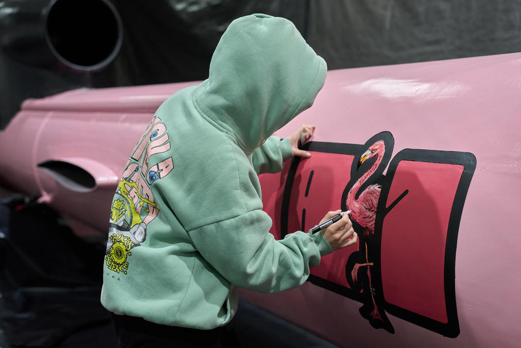 A painter writes "Dana 1" referring to Czech nuclear physicist Dana Drabova on the side of a Flamingo cruise missile, which was paid by a crowdfunding campaign of a Czech organization, Weapons to Ukraine, at the Fire Point factory at an undisclosed location in Ukraine, Sunday, Nov. 16, 2025. (AP Photo/Efrem Lukatsky)