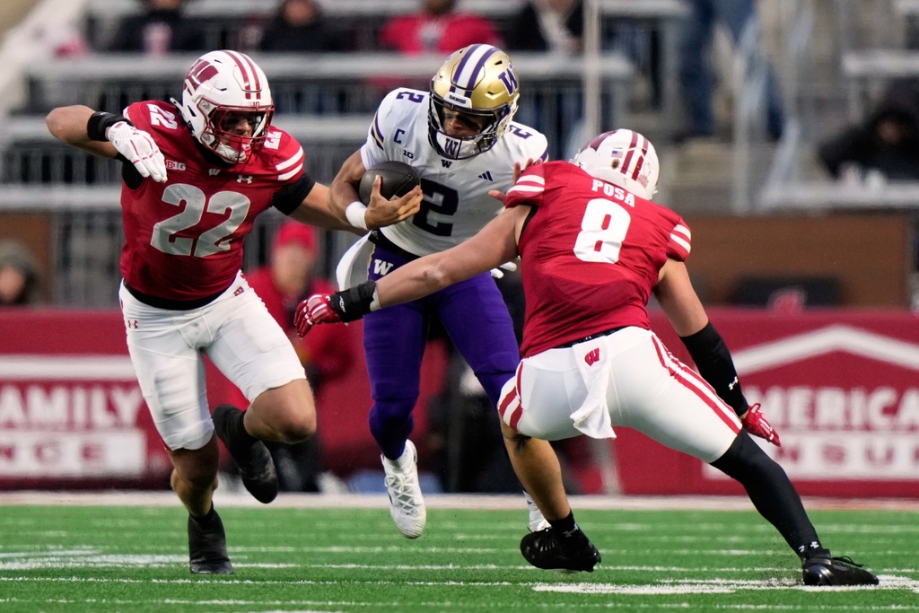 Washington's Demond Williams Jr. tries to run between Wisconsin's Mason Reiger and Mason Posa during the first half of an NCAA college football game Saturday, Nov. 8, 2025, in Madison, Wis. (AP Photo/Morry Gash)