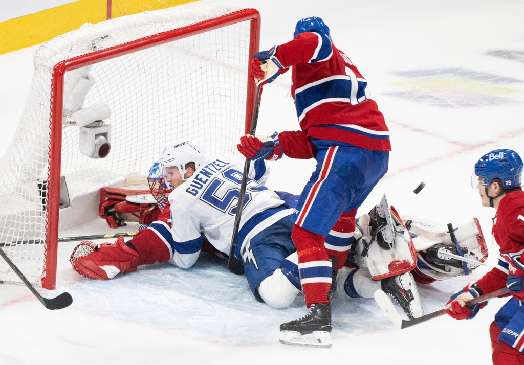 Tampa Bay Lightning's Jake Guentzel (59) crashes into Montreal Canadiens goaltender Jakub Dobes, bottom left, as Canadiens' Nick Suzuki, center, looks for the puck during the second period of Game 4 in a first-round NHL hockey Stanley Cup playoff series in Montreal, Sunday, April 26, 2026. (Christinne Muschi/The Canadian Press via AP)