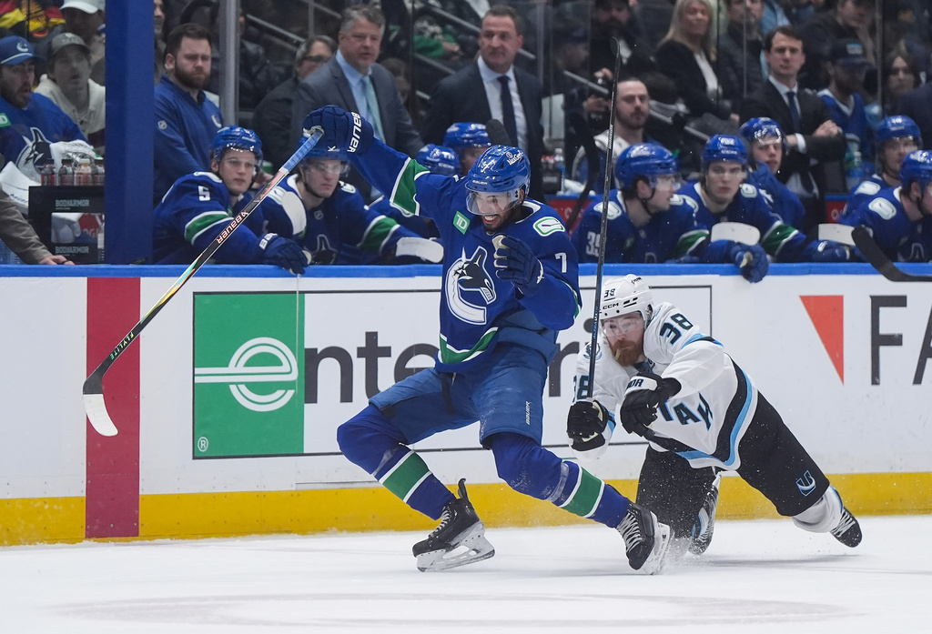 Vancouver Canucks' Pierre-Olivier Joseph (7) stumbles after being checked by Utah Mammoth's Liam O'Brien (38) during the second period of an NHL hockey game, in Vancouver, on Saturday, April 4, 2026. (Darryl Dyck/The Canadian Press via AP)