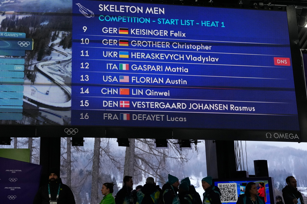 A scoreboard, that indicates that Ukrainian skeleton athlete Vladyslav Heraskevych did not start, is seen at the 2026 Winter Olympics, in Cortina d'Ampezzo, Italy, Thursday, Feb. 12, 2026. (AP Photo/Alessandra Tarantino)