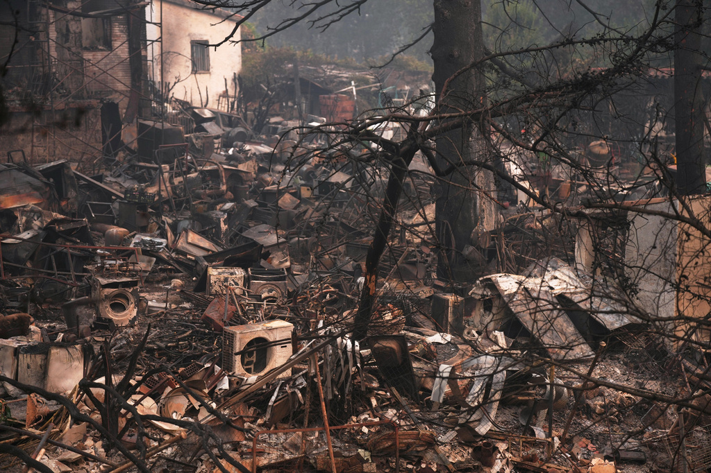 A house and belongings destroyed by a wildfire are photographed as the fire continues to spread near Pelayos de la Presa, Madrid province, Spain, Tuesday, July 28, 2026. (AP Photo/Manu Fernandez)