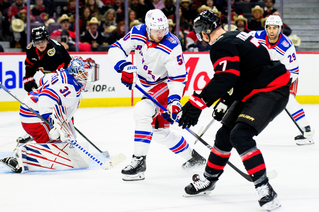 New York Rangers' Will Cuylle (50) and Ottawa Senators' Brady Tkachuk (7) fight for control of the puck during second-period NHL hockey game action in Ottawa, Ontario, Thursday, Dec. 4, 2025. (Spencer Colby/The Canadian Press via AP)