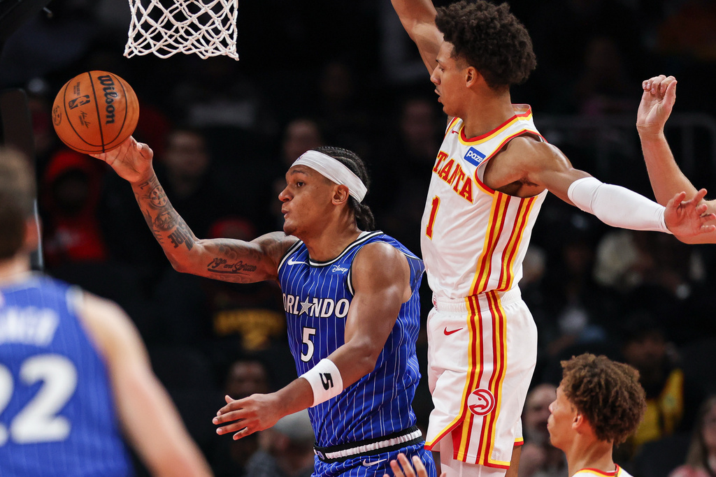 Orlando Magic forward Paolo Banchero (5) passes the ball defended by Atlanta Hawks forward Jalen Johnson (1) during the first half of an NBA basketball game, Tuesday, Nov. 4, 2025, in Atlanta. (AP Photo/Colin Hubbard)