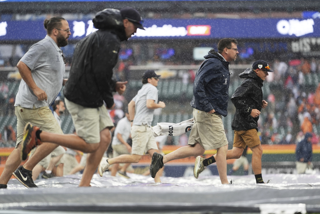 Groundskeepers roll out a tarp during a weather delay during the seventh inning of a baseball game between the Detroit Tigers and the Atlanta Braves, Sunday, Sept. 21, 2025, in Detroit. (AP Photo/Ryan Sun)