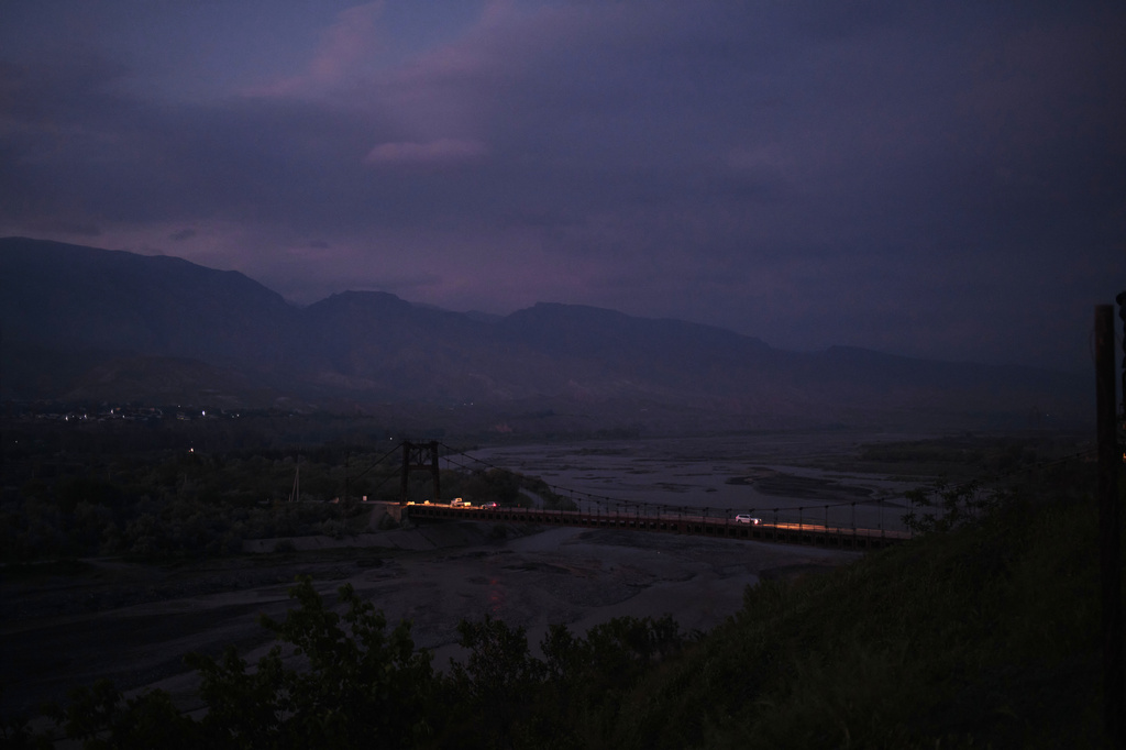 Vehicles cross a bridge after sunset in Panjakent, Tajikistan, Monday, May 4, 2026. (AP Photo/Jon Orbach)