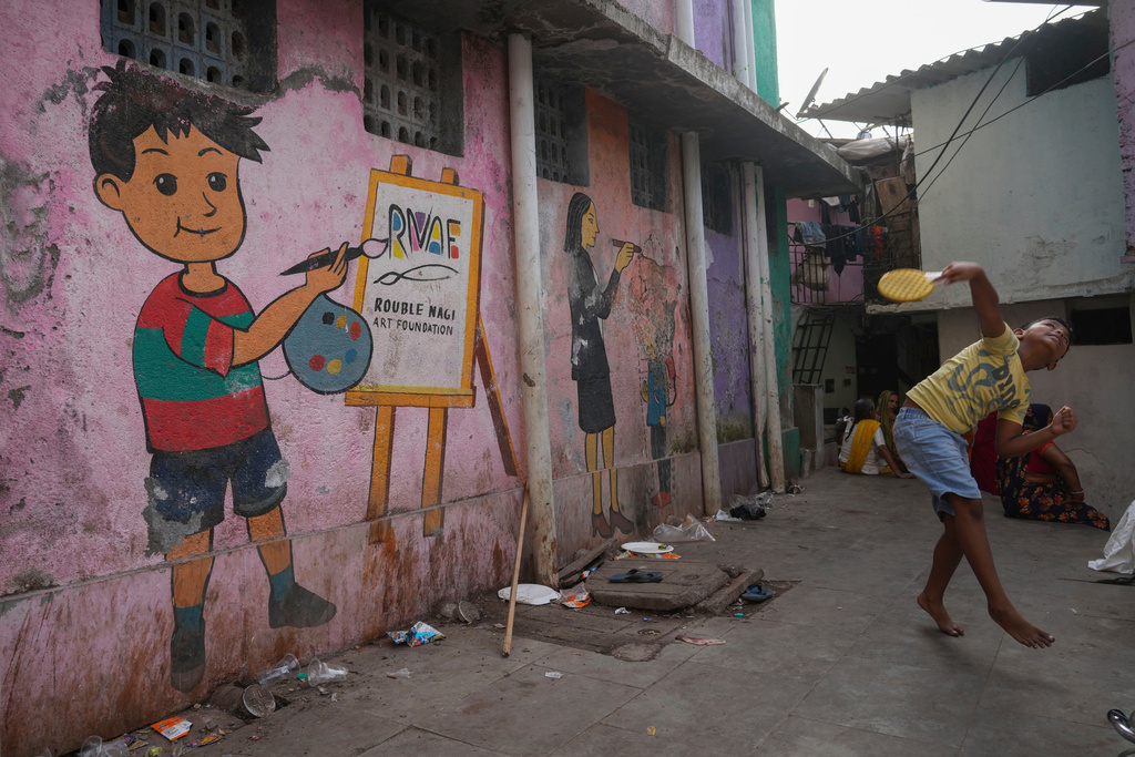 A boy plays near a wall of public toilet that shows a mural by the Rouble Nagi Art Foundation in the Dhobi Ghat area of Mumbai, India, Thursday, Feb. 5, 2026.(AP Photo/Rafiq Maqbool)