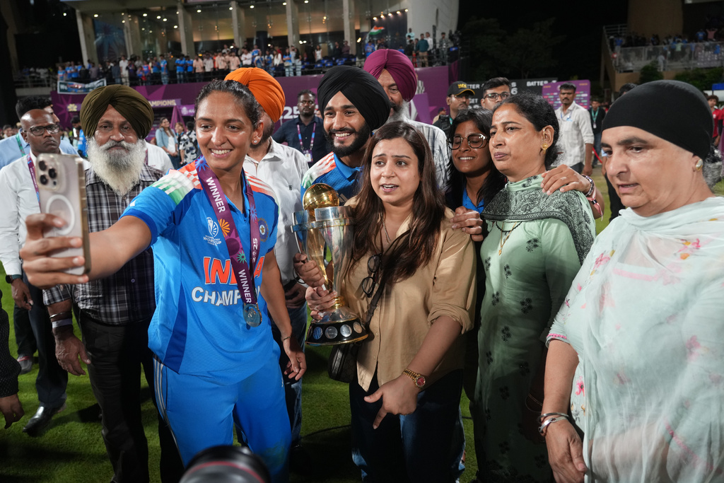 India's captain Harmanpreet Kaur takes selfie with her family members with the winning trophy after their win over South Africa in the ICC Women's Cricket World Cup final match in Navi Mumbai, India, Monday, Nov. 3, 2025. (AP Photo/Rafiq Maqbool)