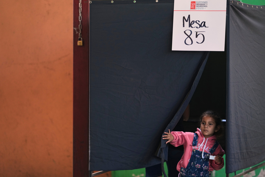 A girl waits while the adult she came with choose her preferences at a polling station during general elections in Santiago, Chile, Sunday, Nov. 16, 2025. (AP Photo/Natacha Pisarenko)