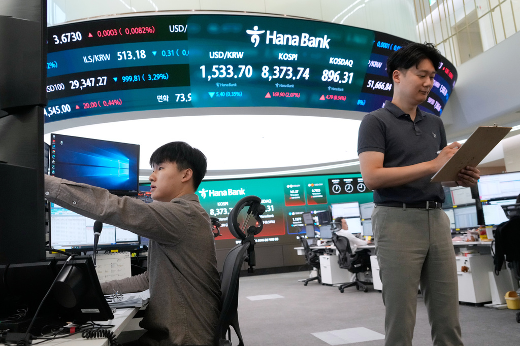 Currency traders work near a screen showing the Korea Composite Stock Price Index (KOSPI) and the foreign exchange rate between U.S. dollar and South Korean won at the foreign exchange dealing room of the Hana Bank headquarters in Seoul, South Korea, Wednesday, June 24, 2026. (AP Photo/Ahn Young-joon)