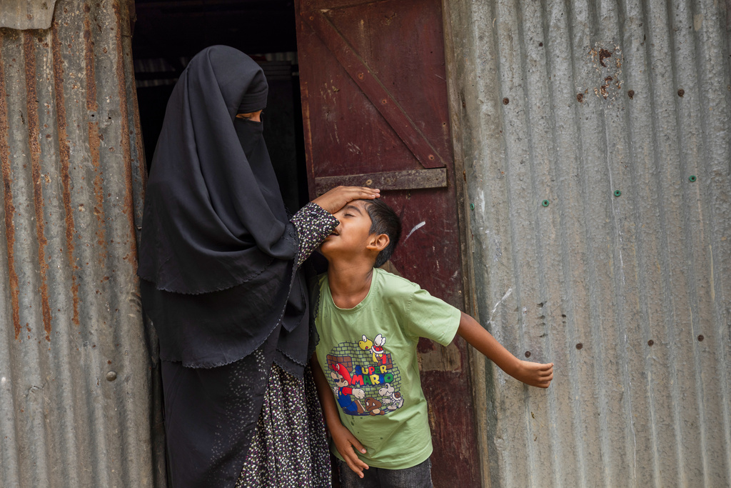 Sadia Islam Sarmin, wife of Mohammad Abdullah Al Mamun touches the forehead of her son at the doorway of their home in Rasulpur village, Mymensingh district, Bangladesh, Friday, April 17, 2026. (AP Photo/Rajib Dhar)