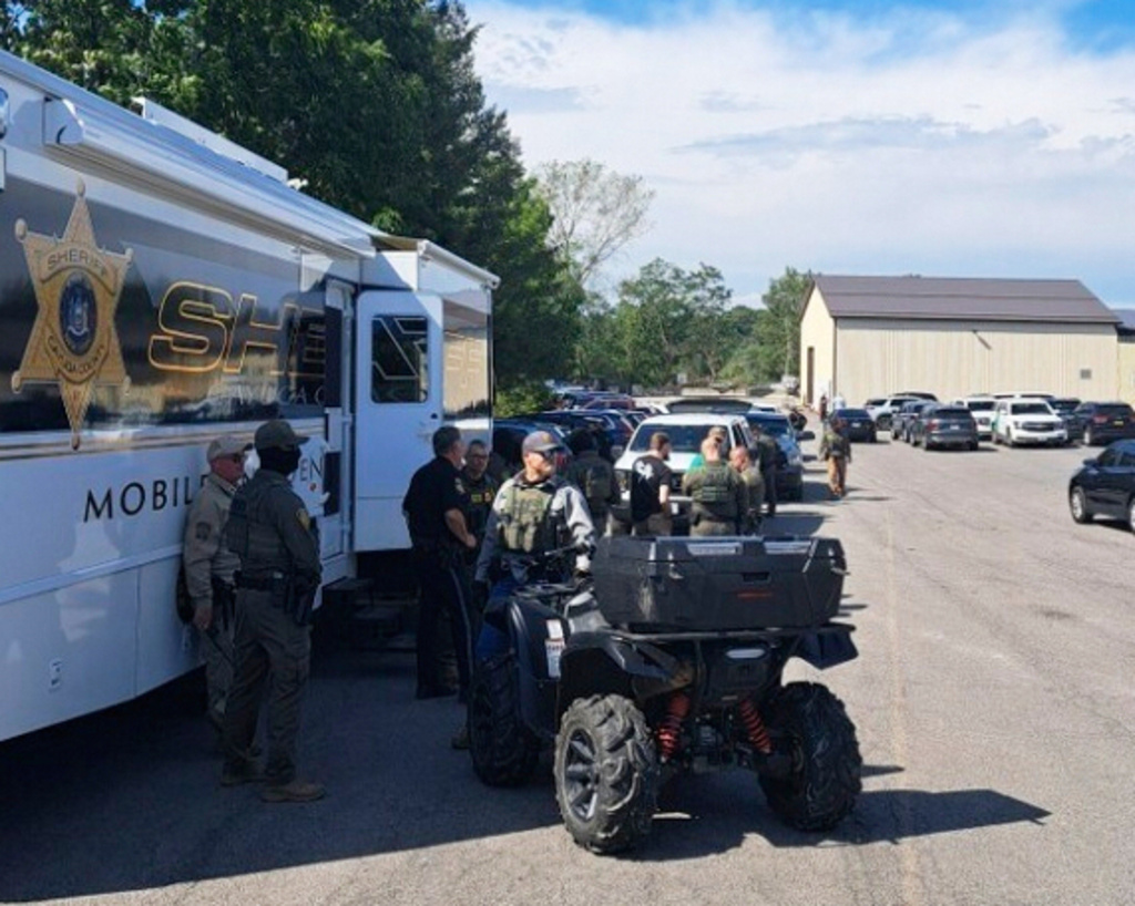 In this photo provided by Rural & Migrant Ministry, law enforcement officers gather outside during a raid on a snack bar manufacturer Friday, Sept. 5, 2025, in Cato, N.Y. (Ana Mendez-Vasquez/Rural & Migrant Ministry via AP)