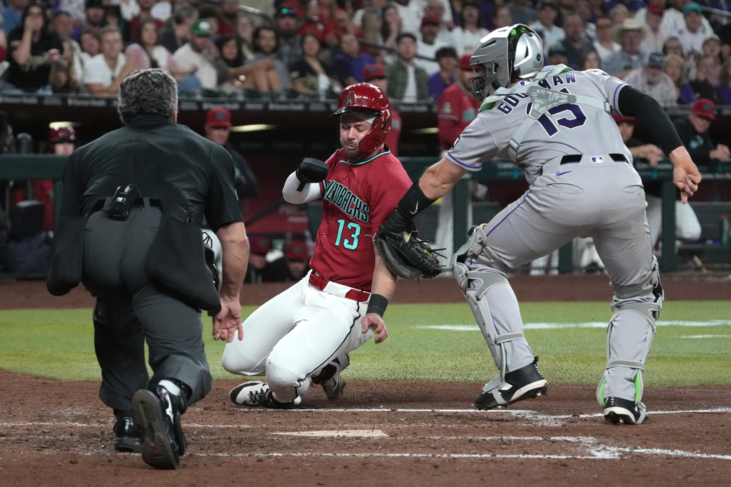 Colorado Rockies catcher Hunter Goodman tags out Arizona Diamondbacks' Tim Tawa (13) trying to score on a ball hit by Ketel Marte in the sixth inning of a baseball game, Saturday, May 23, 2026, in Phoenix. (AP Photo/Rick Scuteri)