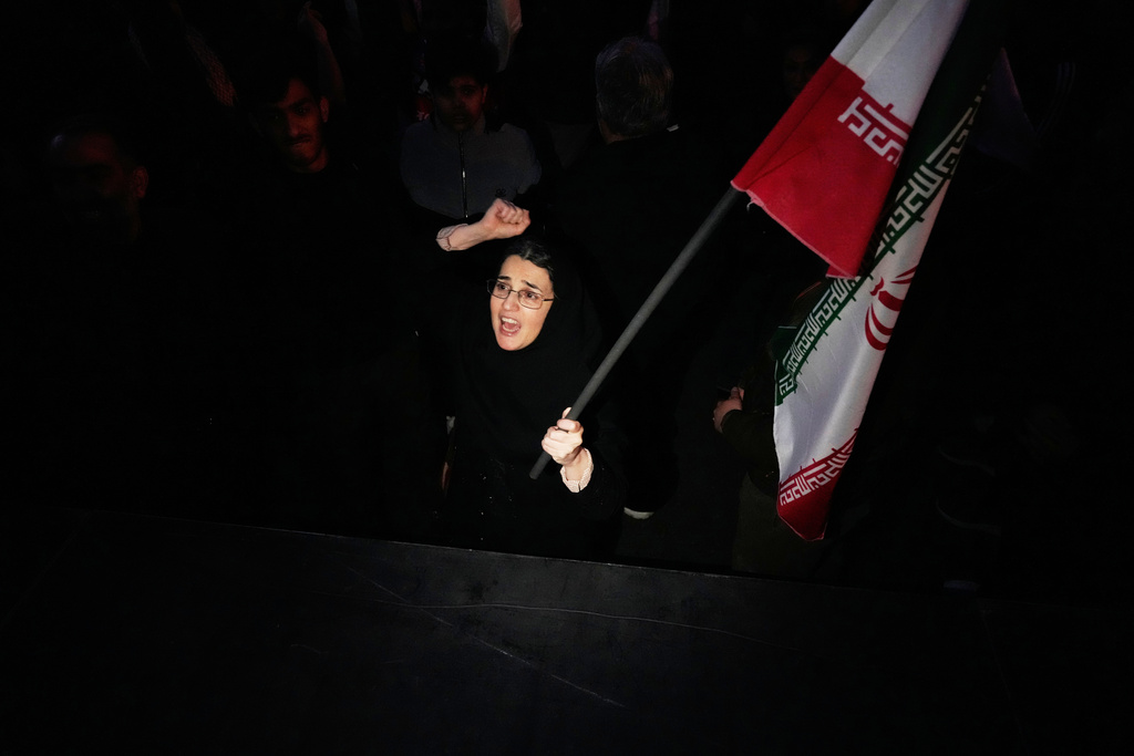 A government supporter chants slogan as she holds an Iranian flag while attending a mourning ceremony after state TV officially announced the death of Iranian Supreme Leader Ayatollah Ali Khamenei, in Tehran, Iran, Sunday, March 1, 2026. (AP Photo/Vahid Salemi)