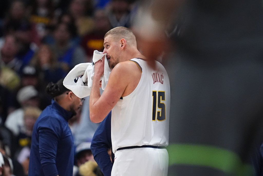 Denver Nuggets center Nikola Jokic uses a towel after taking a hit in the face while facing the Minnesota Timberwolves in the first half in Game 1 of a first-round NBA playoffs basketball series, Saturday, April 18, 2026, in Denver. (AP Photo/David Zalubowski)