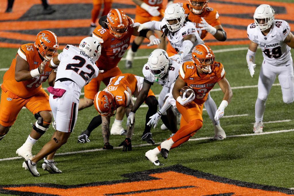 Oklahoma State running back Sesi Vailahi (3) carries the ball past Cincinnati defensive back Jiquan Sanks (9) and linebacker Jonathan Thompson (22) in the first half of an NCAA college football game Saturday, Oct. 18, 2025, in Stillwater, Okla. (AP Photo/Mitch Alcala)