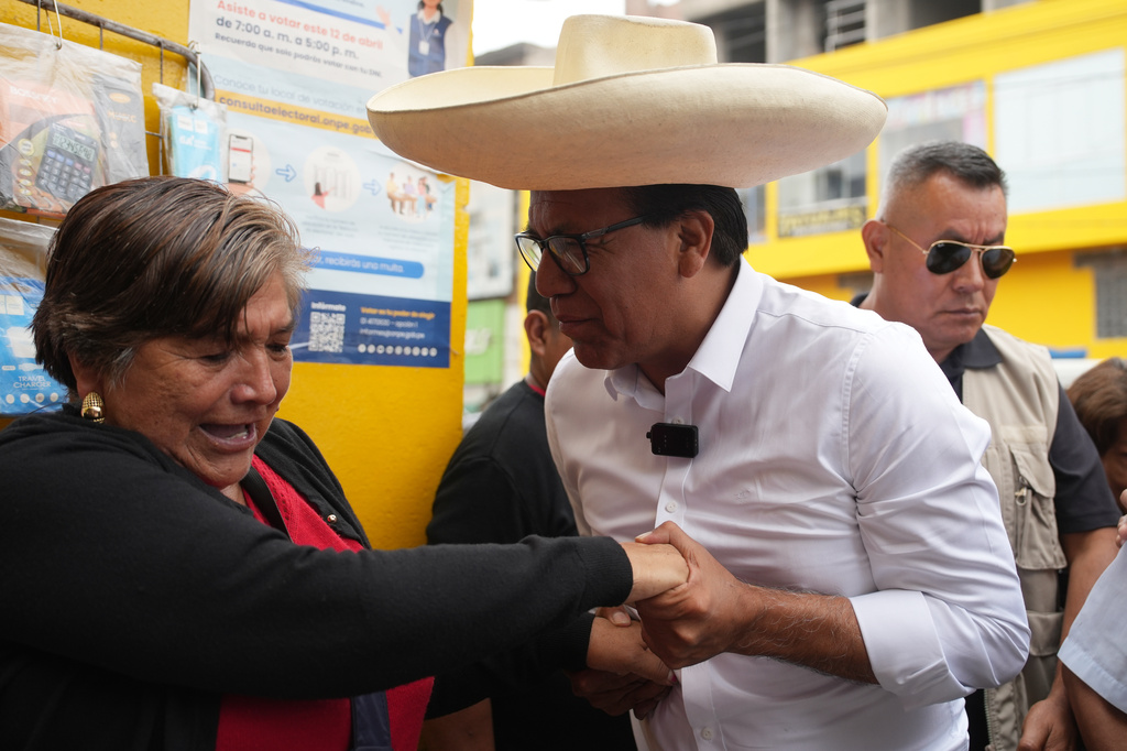 Roberto Sanchez, presidential candidate of Together for Peru party, greets a woman during a visit to a market in Lima, Peru, Tuesday, April 21, 2026. (AP Photo/Guadalupe Pardo)