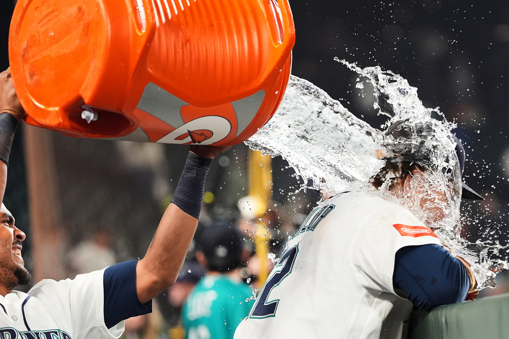 Seattle Mariners' Julio Rodríguez, left, douses teammate Josh Naylor, right, after Naylor hit a walk-off RBI single in the 10th inning to win a baseball game against the Houston Astros, Wednesday, Sept. 23, 2026, in Seattle. (AP Photo/Lindsey Wasson)