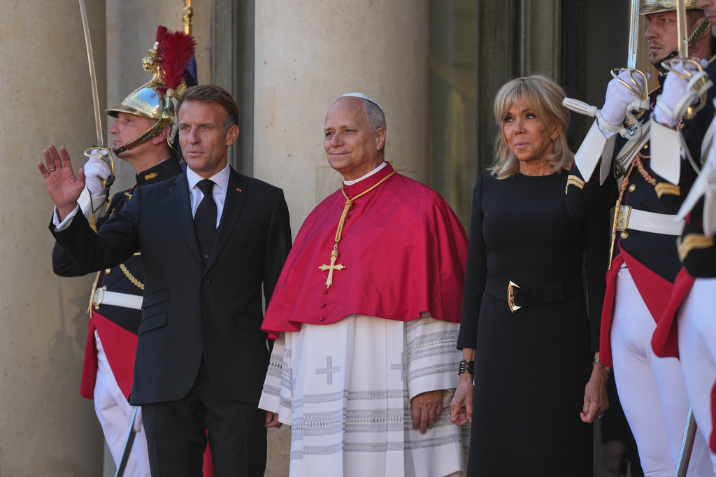 Pope Leo XIV, center, is welcomed by French President Emmanuel Macron, left, and his wife Brigitte as he arrives at the Elysee Palace in Paris, Friday, Sept. 25, 2026. (AP Photo/Gregorio Borgia)