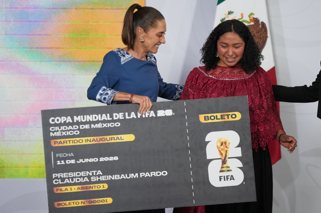 Mexican President Claudia Sheinbaum gives a copy of a symbolic ticket for the 2026 FIFA World Cup opening match to amateur soccer player Yolett Cervantes during her daily news conference at the National Palace in Mexico City, on Friday, May 29, 2026. (AP Photo/Fernando Llano)