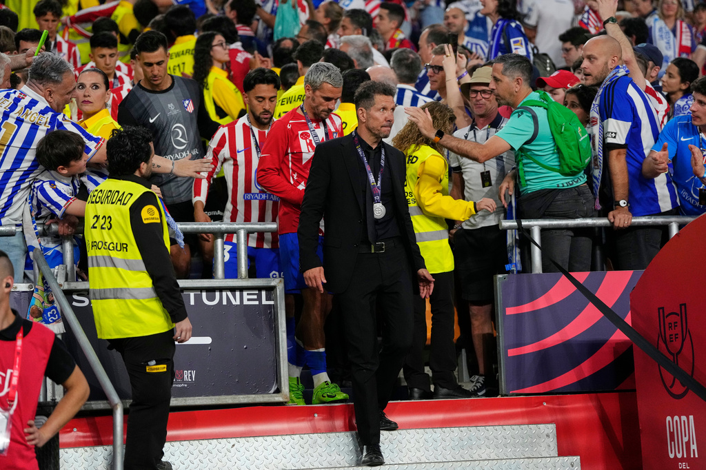 Atletico Madrid's head coach Diego Simeone, centre, and Atletico Madrid's Antoine Griezmann, centre left, walk with silver medals after the Copa del Rey final soccer match between Atletico Madrid and Real Sociedad in Seville, Spain, early Sunday, April. 19, 2026. (AP Photo/Jose Breton)