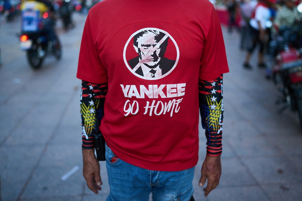 A man wears shirt with a image of U.S. President Donald Trump during a government-organized rally against foreign interference, in Caracas, Venezuela, Thursday, Oct. 30, 2025. (AP Photo/Ariana Cubillos)