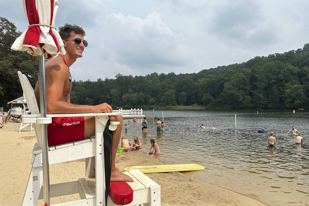 Lifeguard Luke Macchione watches over swimmers and boaters Wednesday, Aug. 6, 2025, on Lake Conewago in Mount Gretna, Pa., a town that springs to life every summer, when its picturesque front porches become filled with energetic cottagers. (AP Photo/Mark Scolforo)