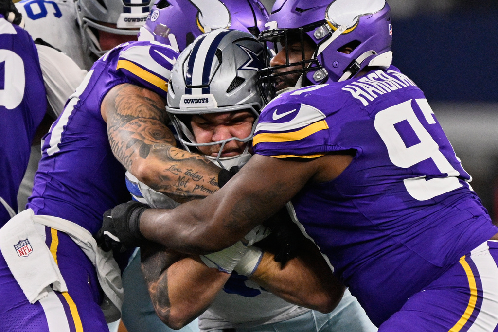 Dallas Cowboys running back Hunter Luepke, center, is stopped by Minnesota Vikings defensive tackle Javon Hargrave, right, and linebacker Blake Cashman during the first half of an NFL football game Sunday, Dec. 14, 2025, in Arlington, Texas. (AP Photo/Jerome Miron)