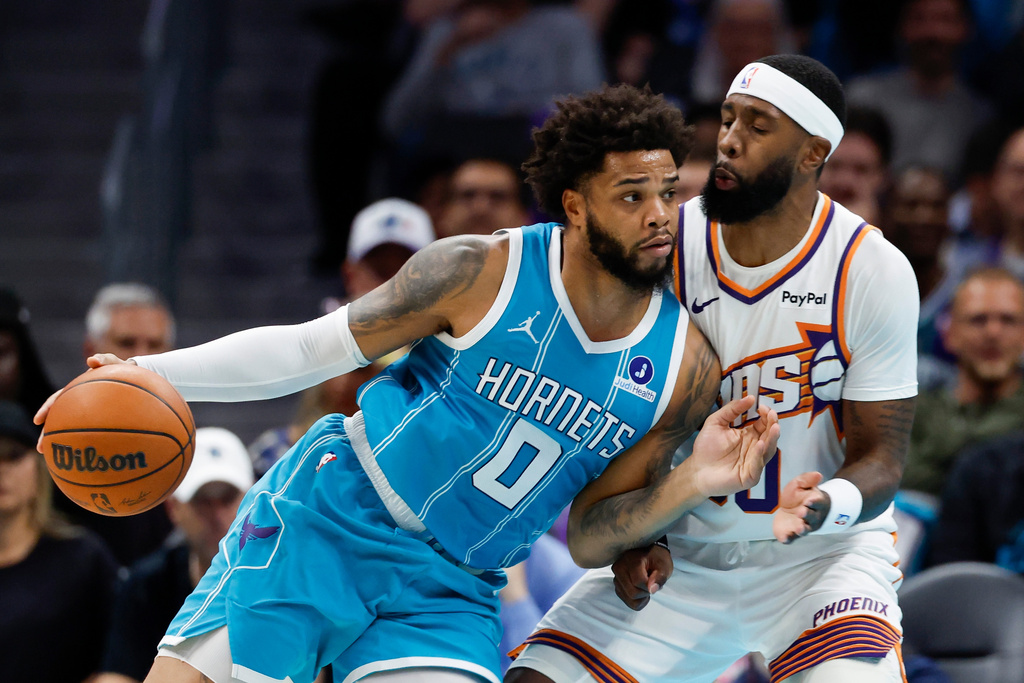 Charlotte Hornets forward Miles Bridges (0) drives into Phoenix Suns forward Royce O'Neale during the first half of an NBA basketball game in Charlotte, N.C., Thursday, April 2, 2026. (AP Photo/Nell Redmond)