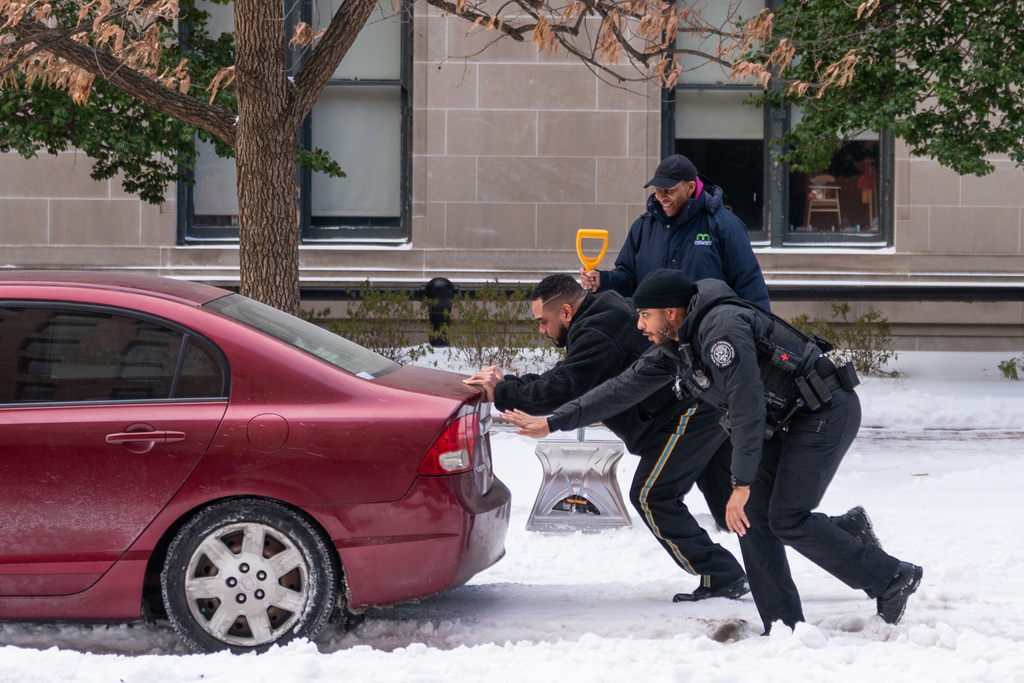 Secret Service officers help a car get out of a build-up of snow, Monday, Jan. 26, 2026, in Washington. (AP Photo/Allison Robbert)