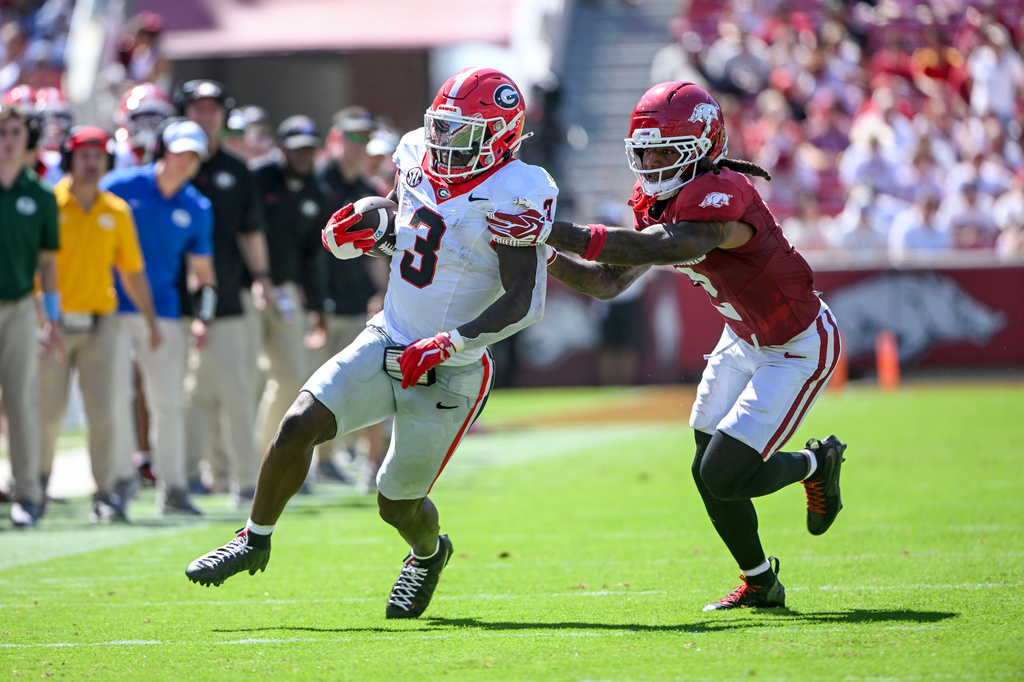 Georgia running back Nate Frazier (3) tries to get away from Arkansas defensive back Shelton Lewis, right, as he runs for a big gain during the second half of an NCAA college football game Saturday, Sept. 19, 2026, in Fayetteville, Ark. (AP Photo/Michael Woods) CORRECTION: Corrects date to Sept. 19 not Sept. 18.