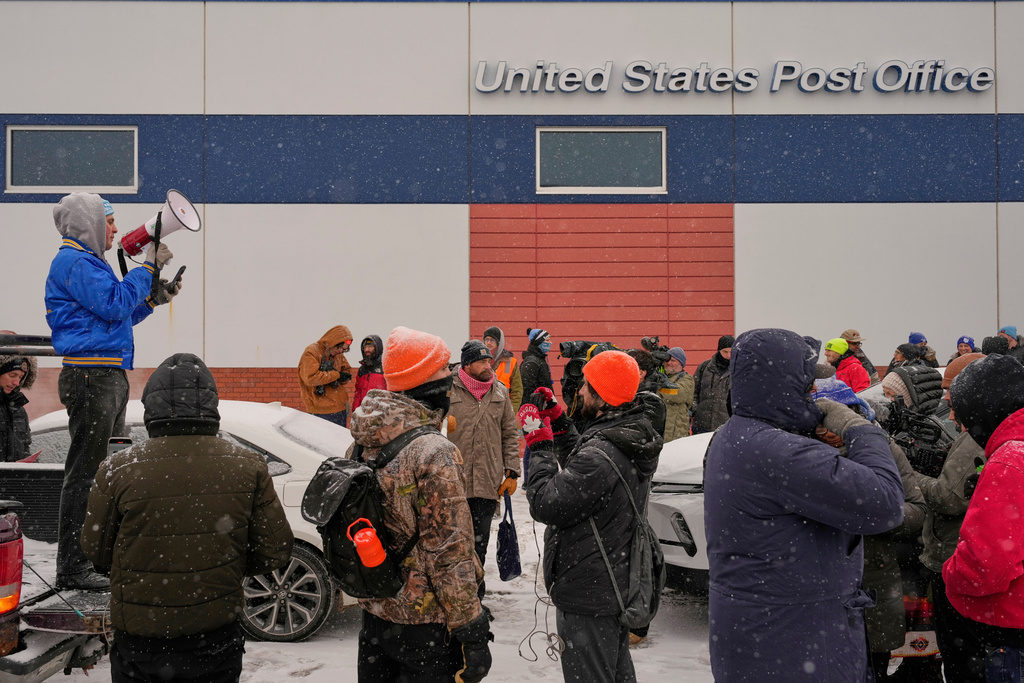 People gather near the post office during a protest, Sunday, Jan. 18, 2026, in Minneapolis. (AP Photo/Yuki Iwamura)