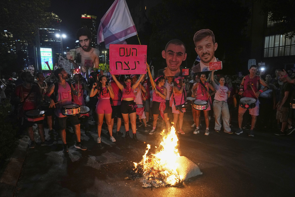 Demonstrators hold photos of Israeli hostages being held in the Gaza Strip during a protest demanding their release from Hamas captivity and an end to the war, in Tel Aviv, Israel, Thursday, Aug. 7, 2025. (AP Photo/Ariel Schalit)