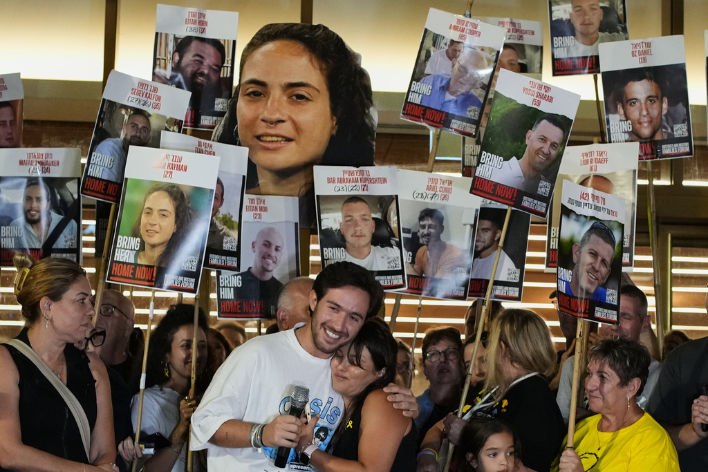 Relatives and supporters of Israeli hostages held by Hamas in the Gaza Strip hold posters with portraits of their loved ones during a gathering following the announcement that Israel and Hamas have agreed to the first phase of a peace plan to pause the fighting, at a plaza known as Hostages Square in Tel Aviv, Israel, Thursday, Oct. 9, 2025. (AP Photo/Ohad Zwigenberg)