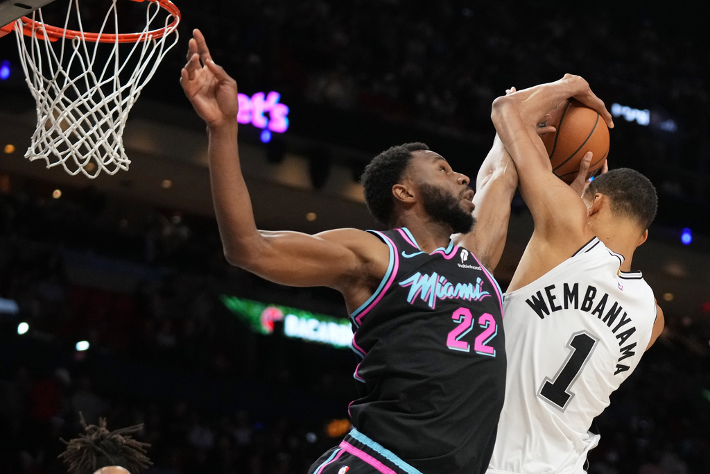 Miami Heat forward Andrew Wiggins (22) goes for a rebound against San Antonio Spurs forward Victor Wembanyama (1) during the second half of an NBA basketball game, Monday, March 23, 2026, in Miami. (AP Photo/Lynne Sladky)