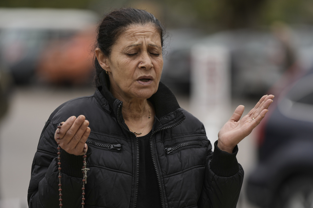 A woman prays while holding a rosary at the tomb of St. Charbel in the northern village of Annaya, Lebanon, Saturday, Nov. 15, 2025. (AP Photo/Hassan Ammar)