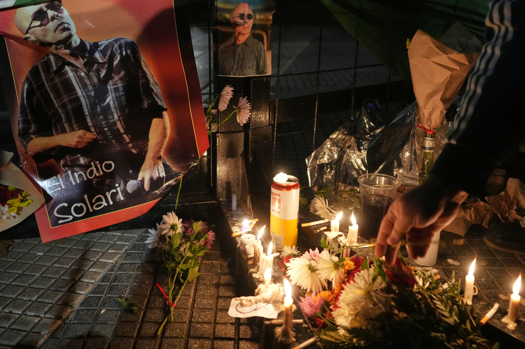 A person lights a candle near a picture of Carlos Alberto Solari, the Argentine singer-songwriter known as "the Indio" who led Patricio Rey y sus Redonditos de Ricota, on the day of his death, at Plaza de Mayo square in Buenos Aires, Argentina, Friday, June 5, 2026. (AP Photo/Gustavo Garello)