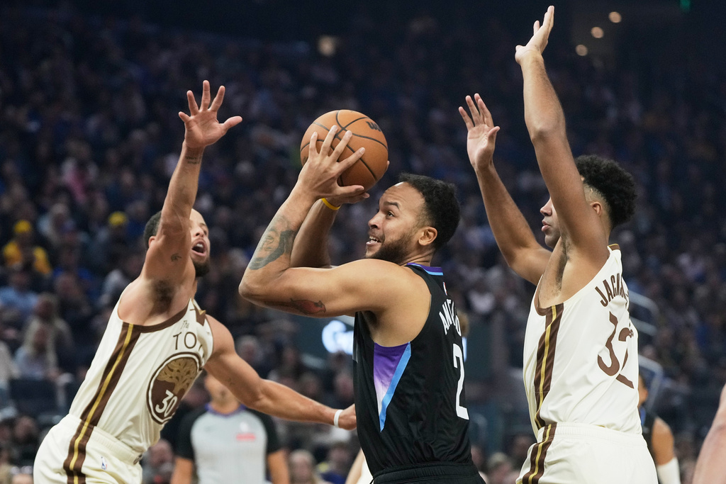Utah Jazz forward Kyle Anderson, middle, looks to shoot between Golden State Warriors guard Stephen Curry, left, and forward Trayce Jackson-Davis during the first half of an NBA basketball game in San Francisco, Monday, Nov. 24, 2025. (AP Photo/Jeff Chiu)