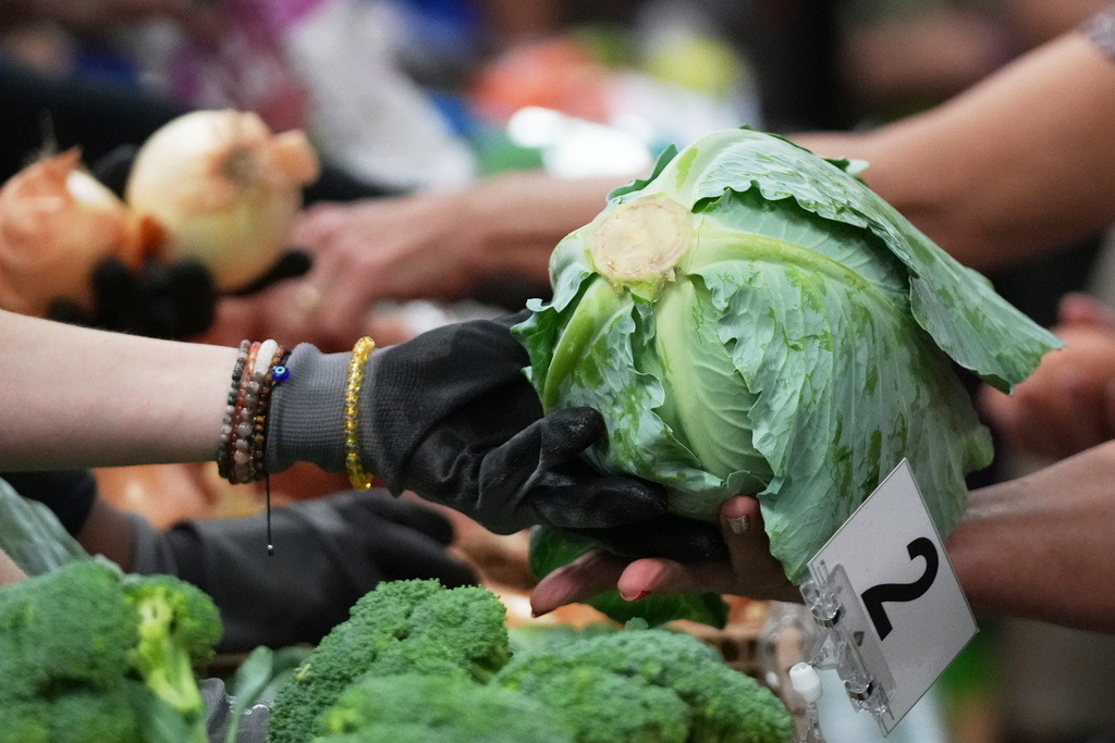 A volunteer hands out produce at a food pantry hosted by the Miami Heat basketball team and the Mobile Food Pantry (MFP) as a day of service in honor of Dr. Martin Luther King Jr., Wednesday, Jan. 14, 2026, in Hollywood, Fla. (AP Photo/Lynne Sladky)