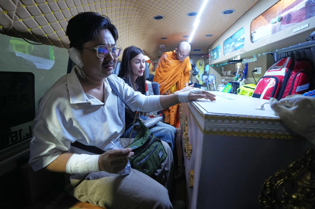 Musical band leader Atipat Wijan sits with the coffin containing the body of his wife Nahatai Sajjalert who was a victim in a music bar fire as it is transferred from a police hospital in Bangkok, Thailand, Tuesday, July 14, 2026. (AP Photo/Sakchai Lalit)