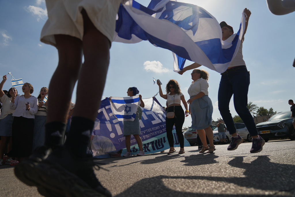 People wave Israeli flags in celebration as they wait outside Beilinson Hospital in Petah Tikva, Israel, where some of the freed hostages are expected to arrive after being released from Hamas captivity in the Gaza Strip, Monday, Oct. 13, 2025. (AP Photo/Francisco Seco)