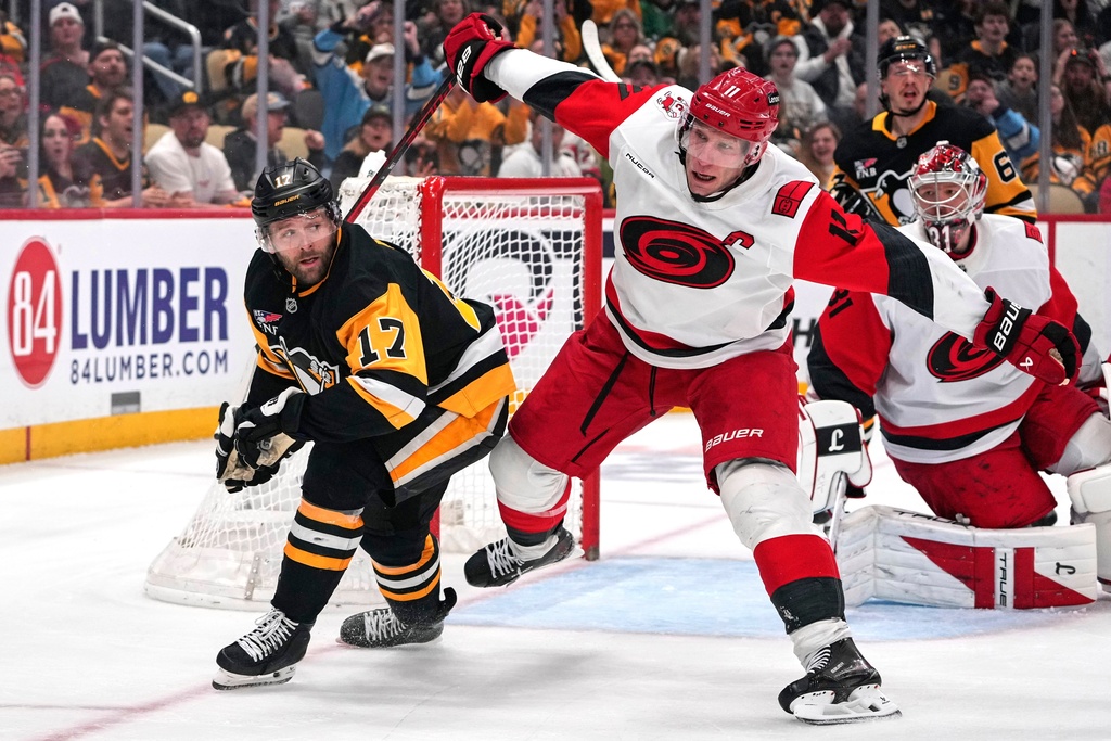 Pittsburgh Penguins' Bryan Rust (17) is defended by Carolina Hurricanes' Jordan Staal (11) during the second period of an NHL hockey game in Pittsburgh, Sunday, March 22, 2026. (AP Photo/Gene J. Puskar)