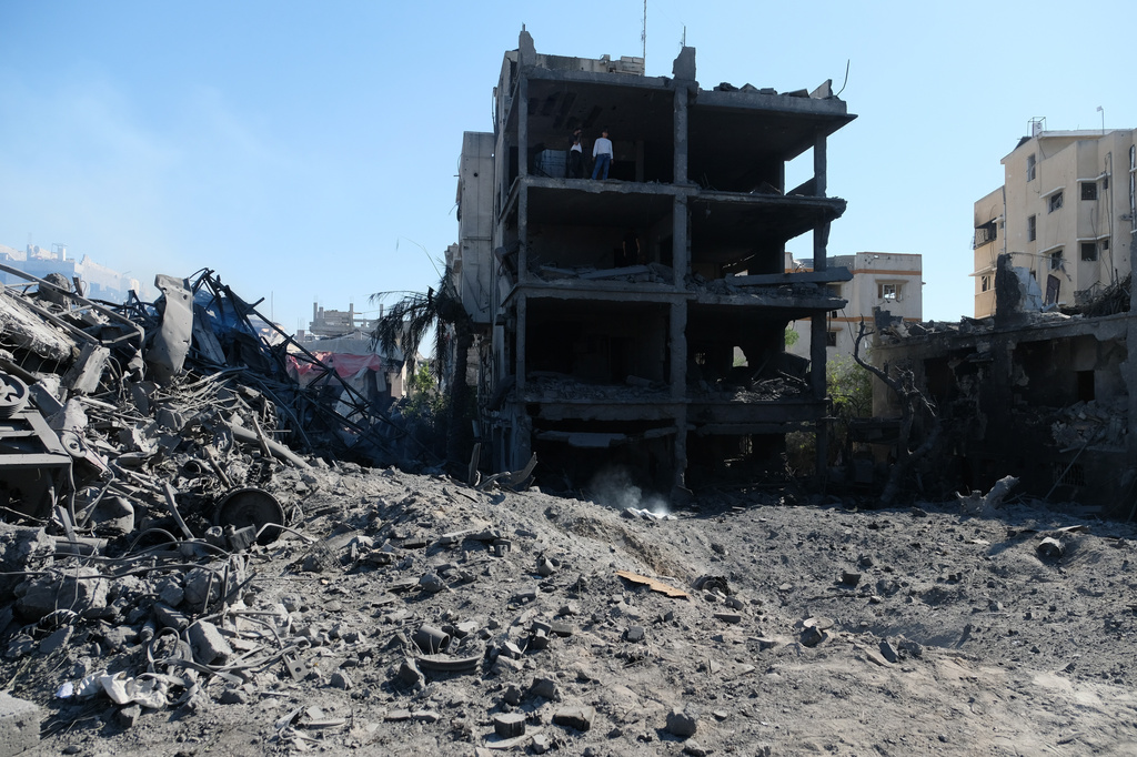 Palestinians gather around a blacksmith shop in Gaza City's Sabra neighborhood after it was hit by an Israeli military strike on Sunday, July 12, 2026. (AP Photo/Jehad Alshrafi)