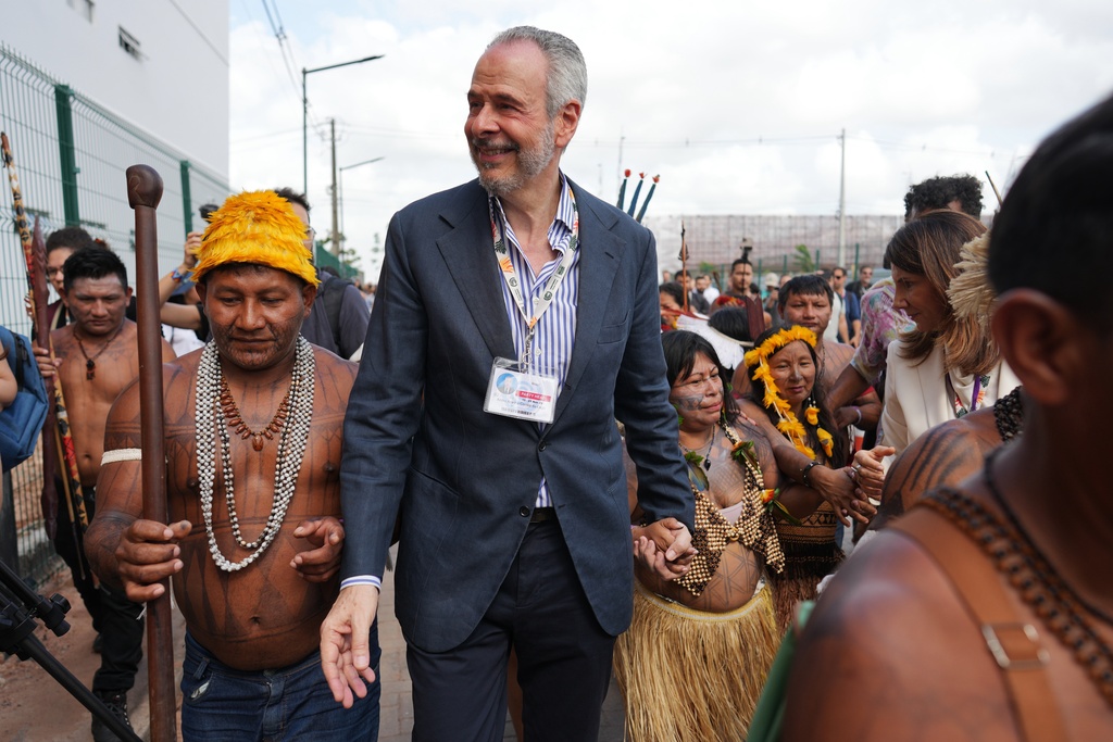 André Corrêa do Lago, COP30 president, center, holds the hand of an Indigenous woman as he walks with a group outside the venue for the COP30 U.N. Climate Summit, Friday, Nov. 14, 2025, in Belem, Brazil. (AP Photo/Andre Penner)