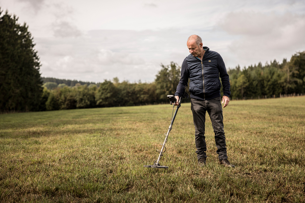Bernard Collard runs a metal detector over a field in the Elsenborn area of Krinkelt, Belgium, Friday, Aug. 21, 2026. (AP Photo/Valentin Bianchi)